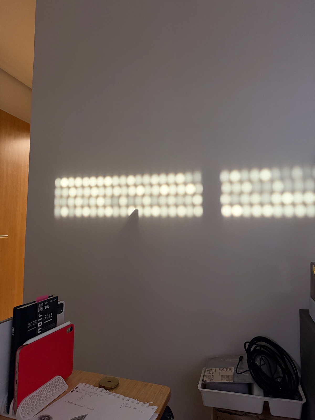 Sunlight through blinds casting a grid of light blocks on a wall